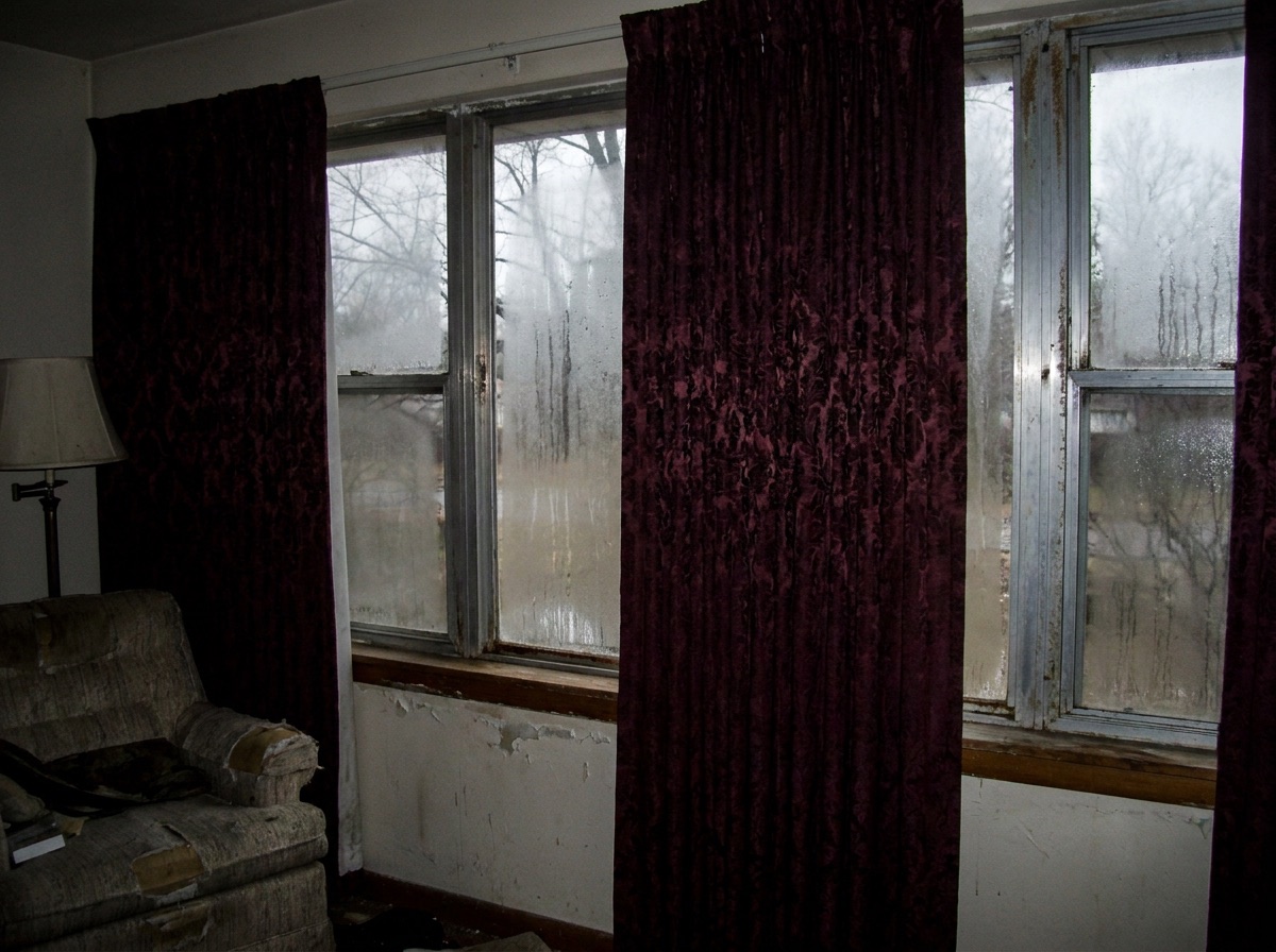 Old drafty single-pane windows in a room before replacement